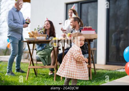 Piccolo toddler con genitori e nonni all'aperto in giardino a casa, festa di compleanno. Foto Stock