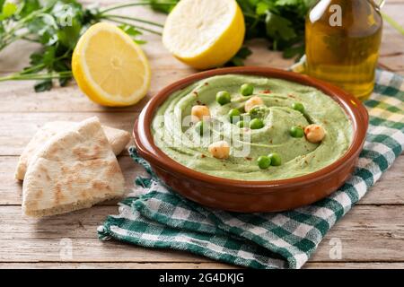 Hummus di pisello verde e pita pane su tavola di legno Foto Stock