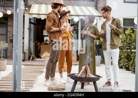 Gruppo di giovani amici appendere fuori da un camino in cortile Foto Stock