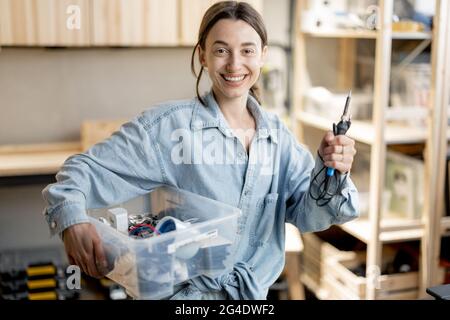 Donna con attrezzi da lavoro nell'officina domestica Foto Stock