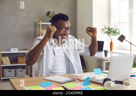 Felice uomo d'affari nero leggere le notizie sul notebook si sente eccitato da nuove opportunità Foto Stock