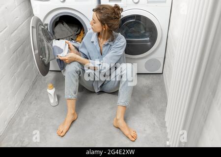 Donna che lava i vestiti a casa Foto Stock