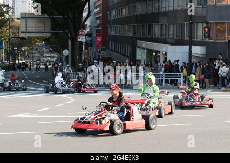 I turisti che guidano vanno i kart mentre indossano i costumi a Tokyo, Giappone Foto Stock