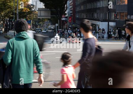 I turisti che guidano vanno i kart mentre indossano i costumi a Tokyo, Giappone Foto Stock