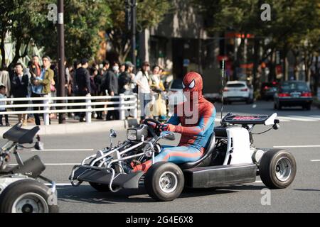 I turisti che guidano vanno i kart mentre indossano i costumi a Tokyo, Giappone Foto Stock