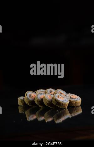 cucina giapponese. panini al sushi cotti su sfondo nero con riflessi. Foto Stock