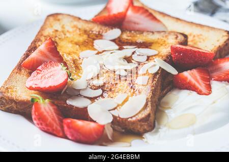 Toast alla francese con fragole, yogurt e sciroppo d'acero su piatto bianco. Concetto di colazione. Foto Stock