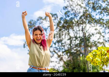 giovane donna latina che festeggia con le mani in alto nell'aria Foto Stock