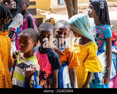MBOUR, SENEGAL - DICEMBRE CIRCA, 2020. Gruppo di adolescenti non identificati in piedi nel parco giochi della scuola, all'aperto in una soleggiata giornata estiva. WAITi Foto Stock