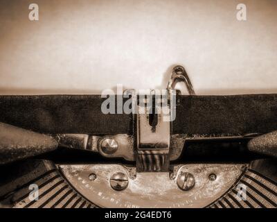 Primo piano della macchina da scrivere con un foglio vuoto di carta caricato in una tonalità seppia Foto Stock