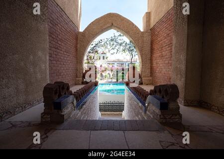 Sharm El Sheikh, Egitto - 15 maggio 2021: Un arco, una struttura in stile africano sullo sfondo di una piscina in un parco circondato da piante. Foto Stock