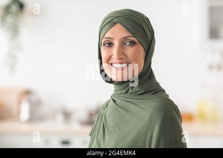 Ritratto di Felice Signora Musulmana matura che indossa Hijab in cucina Foto Stock