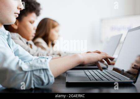 Vista laterale su un gruppo di bambini seduti in fila e utilizzando il computer durante LA lezione DI INFORMATICA a scuola, spazio di copia Foto Stock