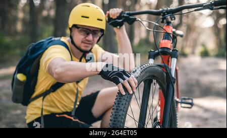 Ciclista uomo che controlla la pressione degli pneumatici Foto Stock