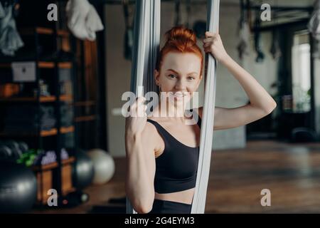 Giovane donna attiva in tuta seduta sulla mosca yoga amaca Foto Stock