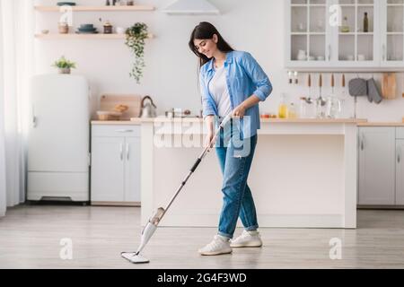 Ritratto della donna che pulisce il pavimento in cucina con mop spray Foto Stock