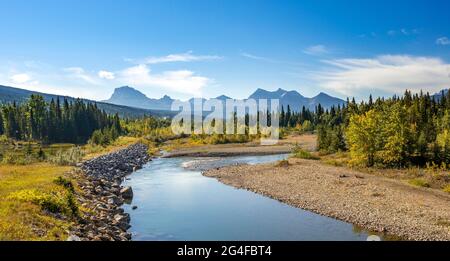 Vista sul fiume verso le montagne, alberi autunnali decidui, Montagne Rocciose al Glacier National Park, Kennedy Creek, Glacier County, Montana, USA Foto Stock