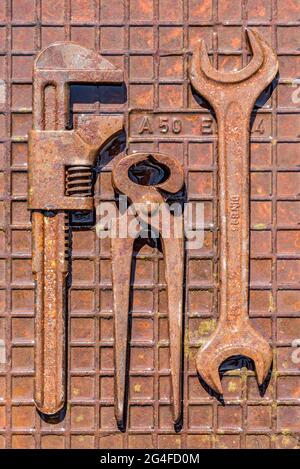 Vecchio utensile con inglese, pinze a becchi, chiave su piastra in ferro umido arrugginito, Germania Foto Stock