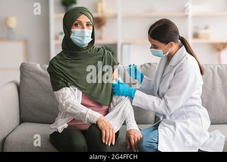 Anziano musulmano Lady paziente ottenere vaccinato contro Covid-19 in interni Foto Stock