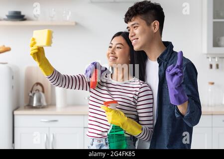 Coppia asiatica amorevole che prende selfie mentre pulisce la cucina Foto Stock