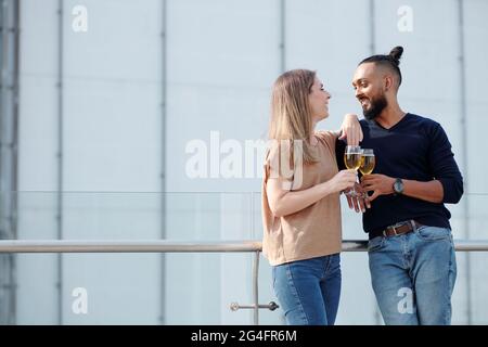 Felice giovane coppia flirtare, parlare e scherzare quando si beve champagne alla festa sul tetto Foto Stock