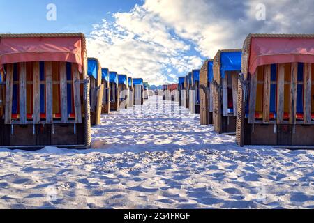 File di sedie da spiaggia ben sistemate sulla sabbia di una spiaggia sul Mar Baltico sotto un cielo azzurro soleggiato e leggermente nuvoloso Foto Stock