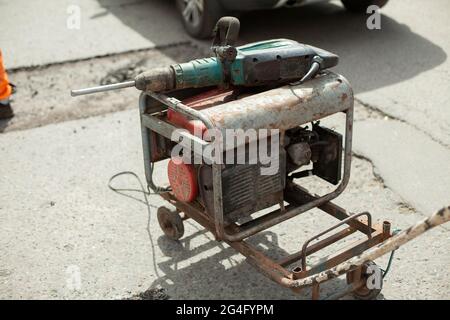 Generatore di benzina di elettricità. Alimentazione all'utensile elettrico. Generatore sulla strada per la riparazione stradale. Foto Stock