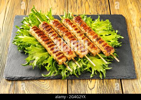 Chevapchichi, antipasto di carne sulla mensola. Le foglie di lattuga completano il piatto di carne. Lula-Kebab. Messa a fuoco selettiva. Foto Stock