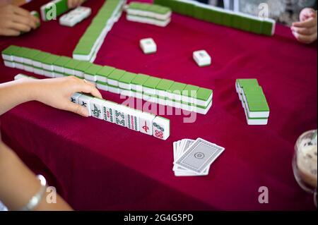 Persone che giocano mahjong tradizionale cinese gioco da tavolo su un tavolo rosso a casa Foto Stock