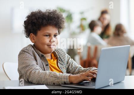 Ritratto di sorridente aloafroamericano che usa un computer portatile in classe, spazio di copia Foto Stock