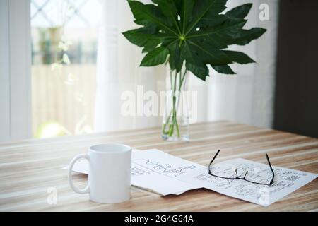 Tazza di caffè, bicchieri e documenti con schemi a blocchi sul tavolo a casa Foto Stock