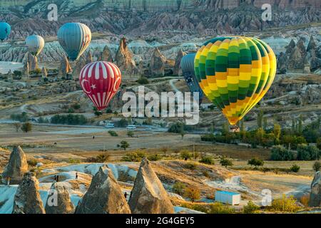 Cappadocia, 05 ottobre 2018: Palloncini colorati ad aria calda che volano sopra formazioni rocciose di campagna al mattino presto a Cappadocia, Goreme, Turchia Foto Stock