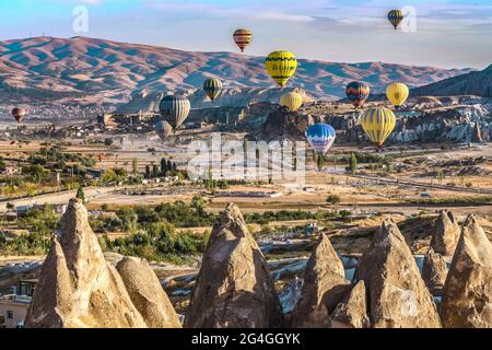 Cappadocia, 05 ottobre 2018: Palloncini colorati ad aria calda che volano sopra formazioni rocciose di campagna al mattino presto a Cappadocia, Goreme, Turchia Foto Stock