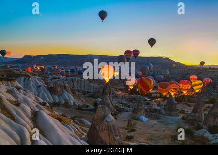 Cappadocia, 05 ottobre 2018: I palloni colorati ad aria calda iniziano a volare sopra le formazioni rocciose di campagna all'alba, Cappadocia, Goreme, Turchia Foto Stock