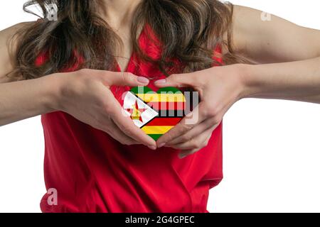 Love Zimbabwe la donna tiene un cuore sotto forma di bandiera dello Zimbabwe sul petto. Concetto di patriottismo. Foto Stock