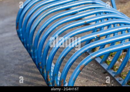 Parcheggio per biciclette in tubi di acciaio blu curvi, fondo astratto di trasporto urbano Foto Stock