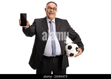Uomo d'affari maturo che tiene una palla di calcio e un telefono cellulare solato su sfondo bianco Foto Stock
