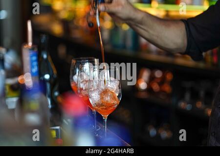 Tre bicchieri di cocktail al bar. Il barman versa un bicchiere di spumante con Aperol. Foto Stock