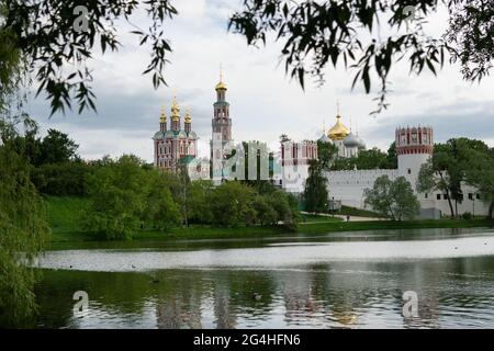 Vista del monastero Novodevichy di Mosca in primavera, con foglie di albero sfocate in primo piano Foto Stock