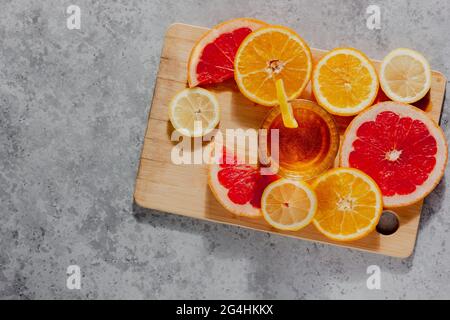 Cocktail salutare servito in un bicchiere su fondo di cemento. Arance, limoni, pompelmo con dolce freddo e tonico acido. Posiziona per il testo del menu Foto Stock