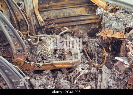 Automobili arrugginite bruciate su una strada cittadina, vandalismo. Fuoco di messa a fuoco per auto da vandali e danni alla proprietà Foto Stock