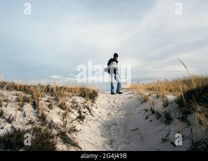 Uomo su una duna spiaggia di sabbia del New England in inverno Foto Stock
