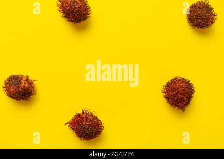 qualche goccia di frutta di rambutan sul tavolo colorato isolato, semplice stile minimalista, vista frome sopra, piatto posa Foto Stock