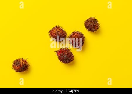 qualche goccia di frutta di rambutan sul tavolo colorato isolato, semplice stile minimalista, vista frome sopra, piatto posa Foto Stock