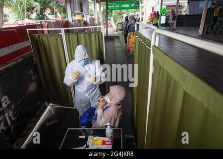 Un operatore sanitario vestito con tuta protettiva conduce un test antigenico su un passeggero alla stazione Manggarai di Giacarta. PT KAI Commuter Indonesia ha condotto test casuali sull'antigene sui passeggeri KRL per prevenire la diffusione di Covid-19. La prova è stata effettuata in diverse stazioni quali Bekasi, Bogor, Cikarang, Tangerang, Manggarai, E Tanah Abang prendendo di mira 150-200 test antigenici al giorno. Covid-19 in Indonesia continua a salire e rompere i record. Lunedì (21/6/2021) sono stati registrati altri 14,536 casi. Sulla base dei dati del Ministero della Salute, questo nuovo caso porta il totale positivo Foto Stock