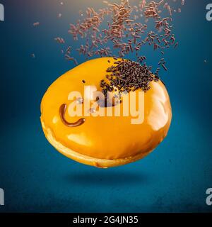 Ciambella dolce volante con faccia divertente su sfondo blu Foto Stock