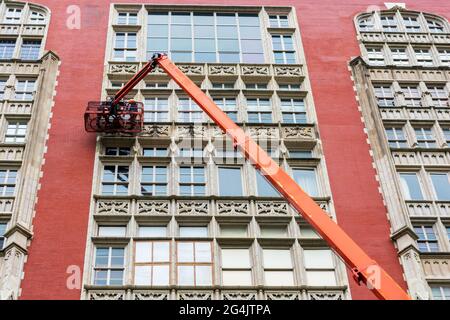 Addetti alla pulizia professionale dei finestrini ad alto sollevamento sulla piattaforma di sollevamento del braccio telescopico. Due lavoratori utilizzano attrezzature specializzate per l'accesso e cl Foto Stock