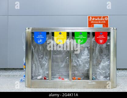 BANGKOK, THAILANDIA - 21 giu 2021: Riciclaggio di selezione giallo, verde, blu e rosso riciclare contenitori trasparenti con simbolo di riciclaggio sullo sfondo della parete Foto Stock