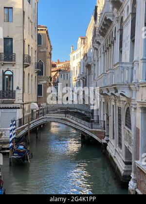 Bel ponte su un piccolo canale fiancheggiato, su sfondo colorato edificio, Venezia, Italia, durante la crisi di Lockdown COVID-19 Foto Stock