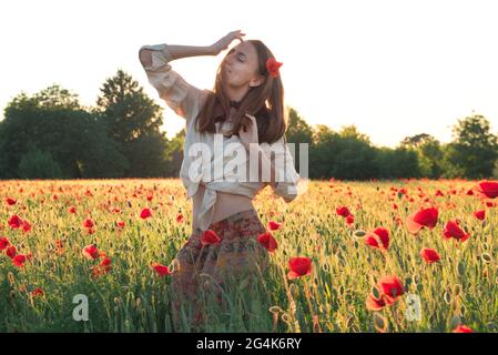 Giovane donna che balla sul campo di papavero dalla parte posteriore Foto Stock